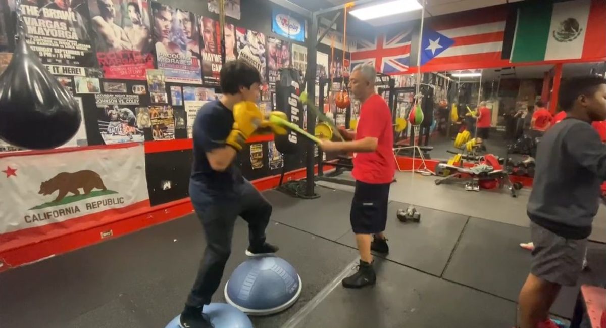 Coach Jamal Valdez-Allen running a reflex and balance drill with a boxer at Lightning Boxing Club, Oakland